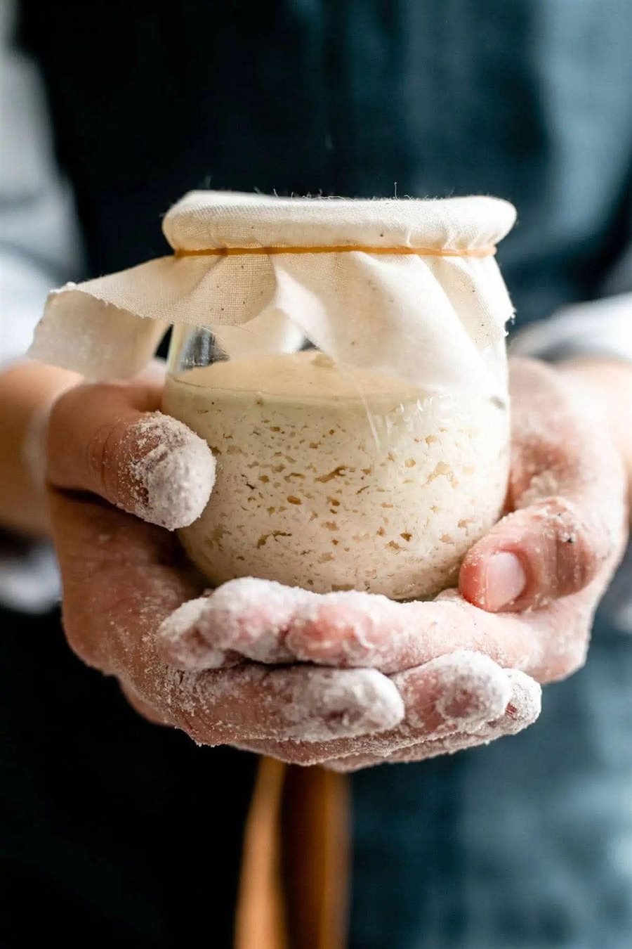 Bocal de levain dans des mains farinées